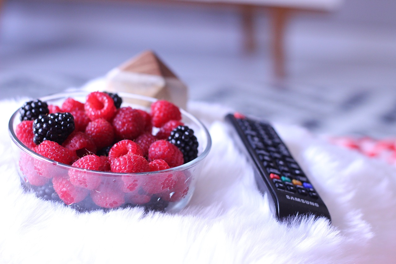 Persone che mangiano davanti alla TV, distratte e con cibo in mano, illustrando il tema dell'articolo.